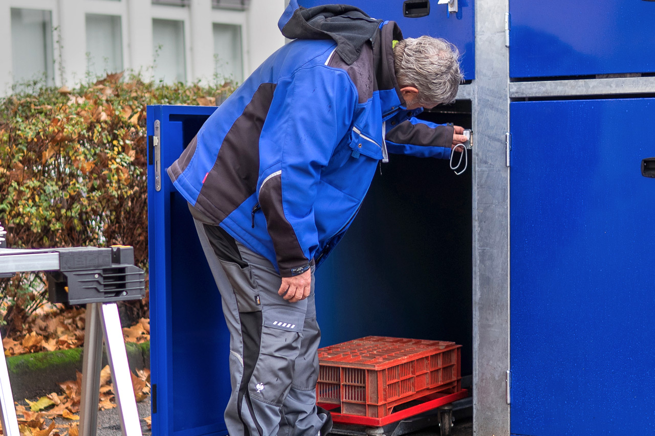 Die Reparatur an einer Fahrradbox mit Rollwagen, Kabeln und einem Mitarbeiter in voller Montur.